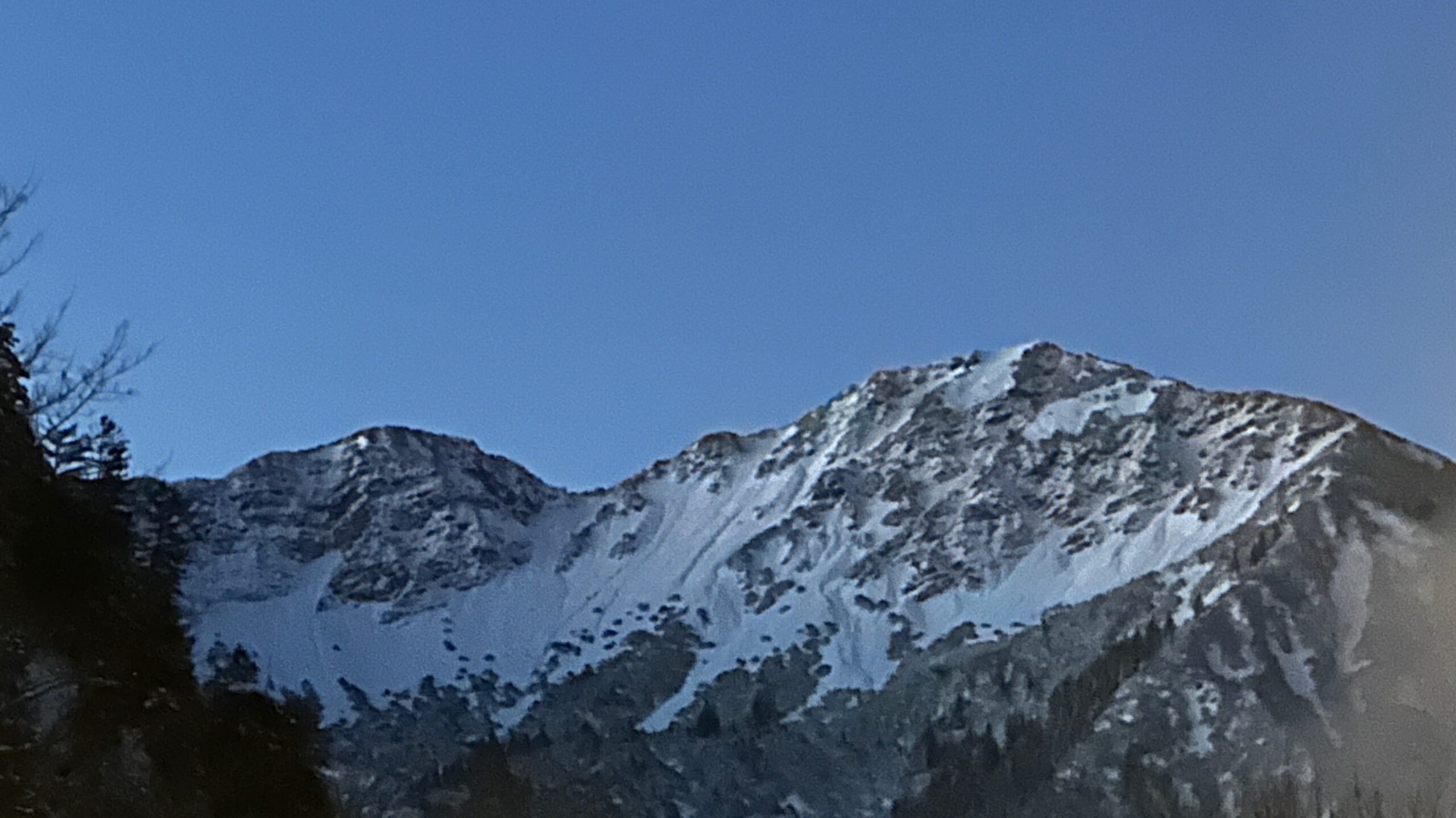 Schneebedeckte Berggipfel der Ammergauer Alpen unter klarem, blassblauem Himmel, aufgenommen bei Oberammergau.