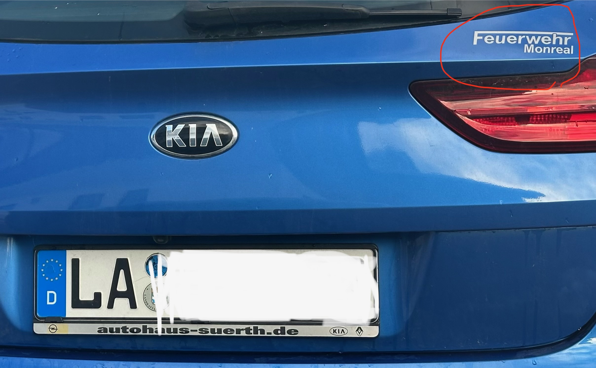 Rückseite eines blauen Kia mit Aufkleber „Feuerwehr Monreal“ am Heck in Oberammergau.