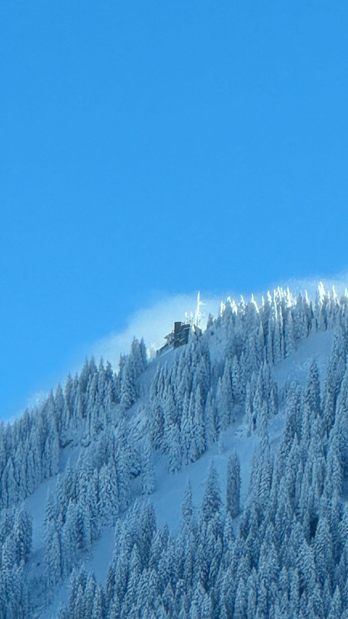 Schneebedeckte Bergstation am Laber in Oberammergau vor klarem blauem Himmel.